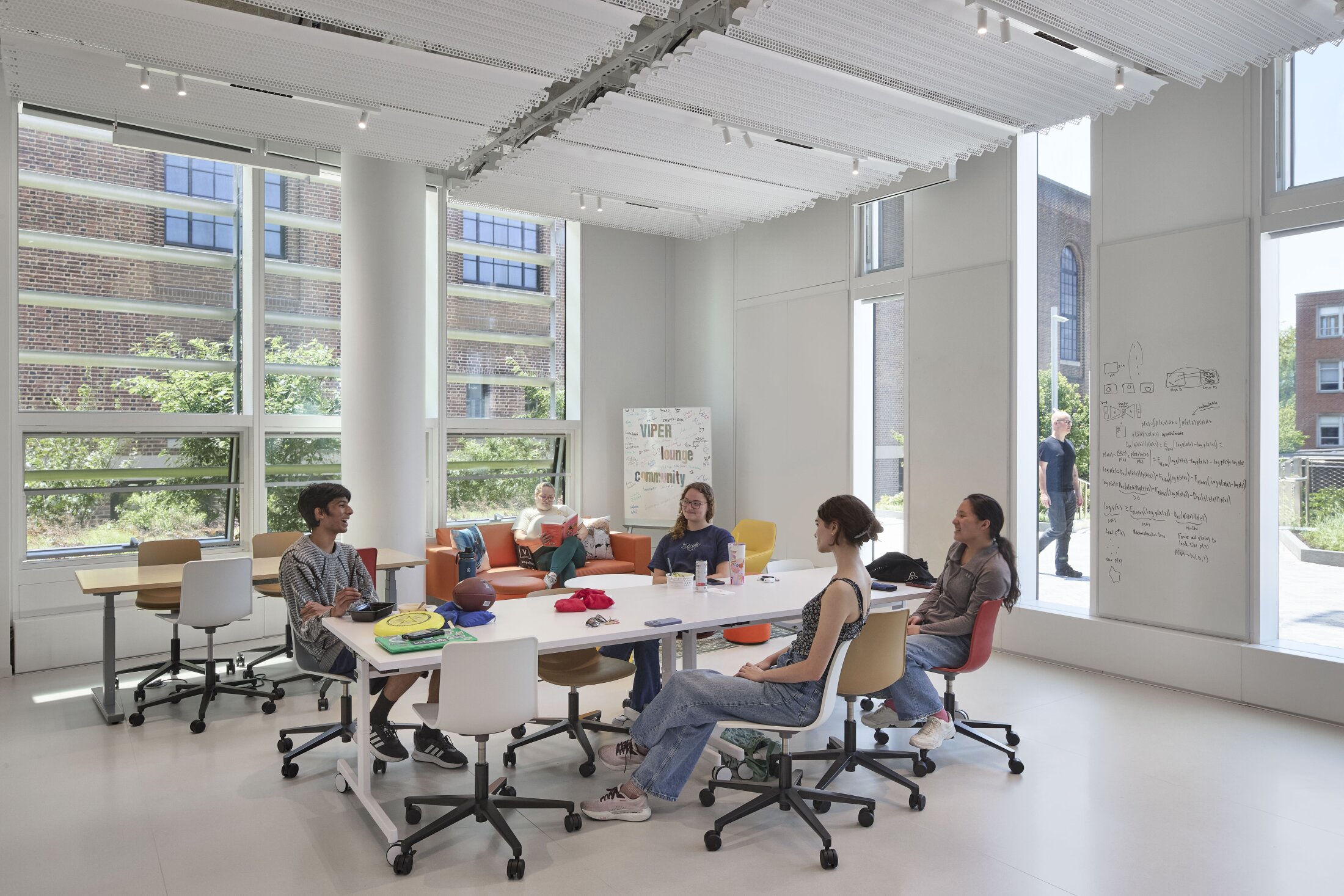 Project by Behnisch Architekturbuero, The Vagelos Laboratory for Energy Science & Technology, University of Pennsylvania. Students are sitting around a table in a bright room with large windows and a whiteboard.
