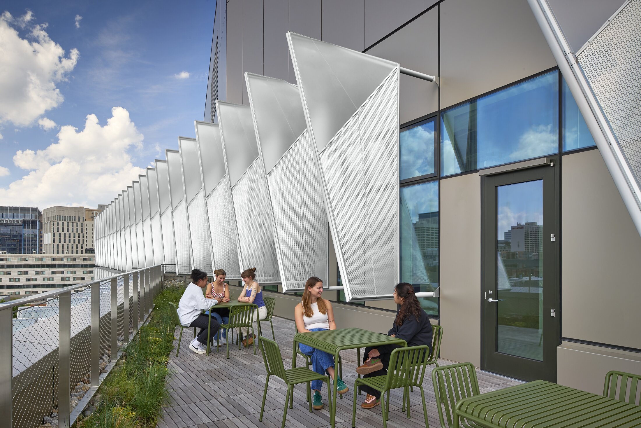 Project by Behnisch Architekturbuero, The Vagelos Laboratory for Energy Science & Technology, University of Pennsylvania. Students are sitting at tables on the green terrace. The sun protection can be seen in the background.