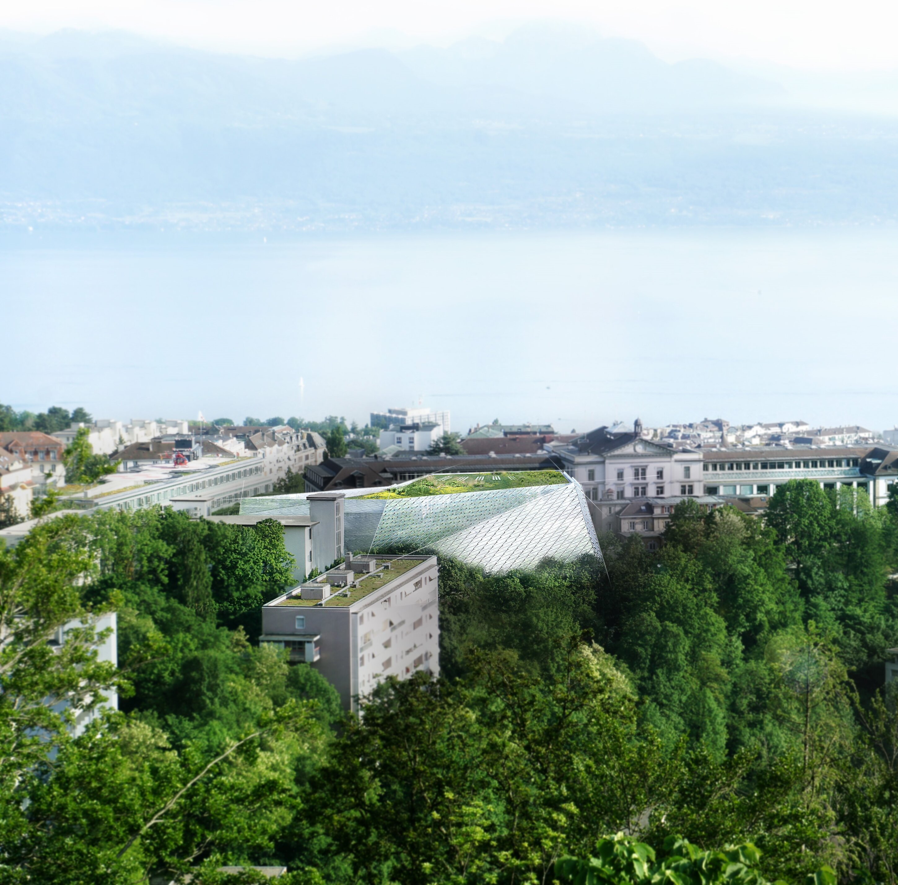 Project by Behnisch Architekturbuero, AGORA P&ocirc;le de recherche sur le cancer. Elevated view of a town with trees and rooftops, featuring a modern glass-roofed building, with a large lake and mountains in the background.