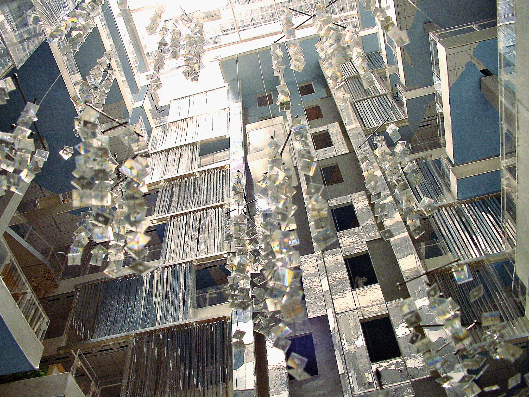 Project by Behnisch Architekturbuero, Genzyme Center. Upward view of the multi-story atrium with suspended reflective panels, glass walkways, and layered balconies lit by daylight from above.
