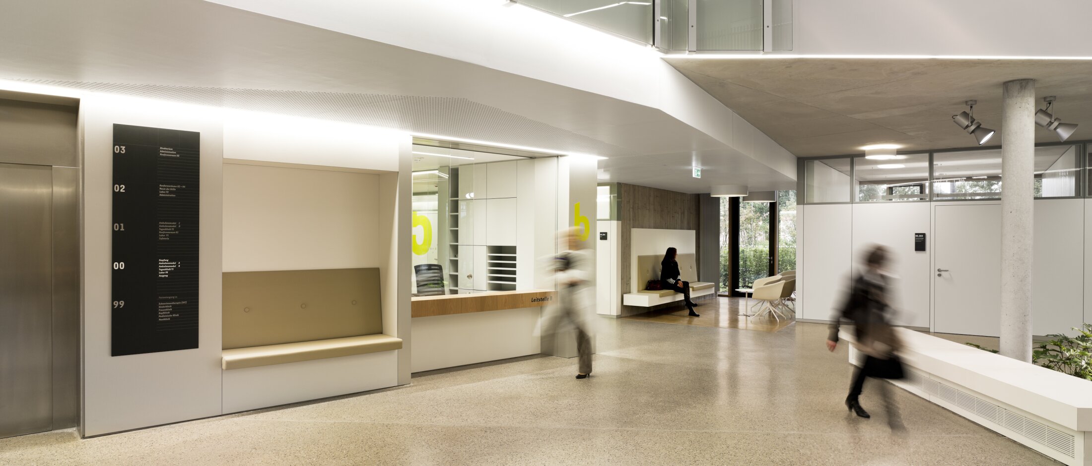 Project by Behnisch Architekturbuero, NCT National Center for Tumour Diseases. Modern lobby with reception desk, seating areas, elevator, and people walking through the bright, minimalist interior space.