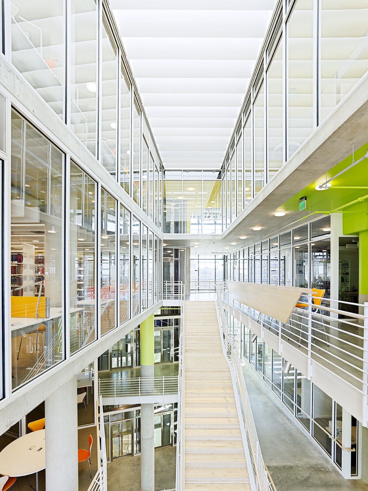 Project by Behnisch Architekturbuero, The John and Frances Angelos Law Center. Bright multi-level interior with glass walls, walkways, and stairs connecting floors. Some offices and study areas are visible through windows.