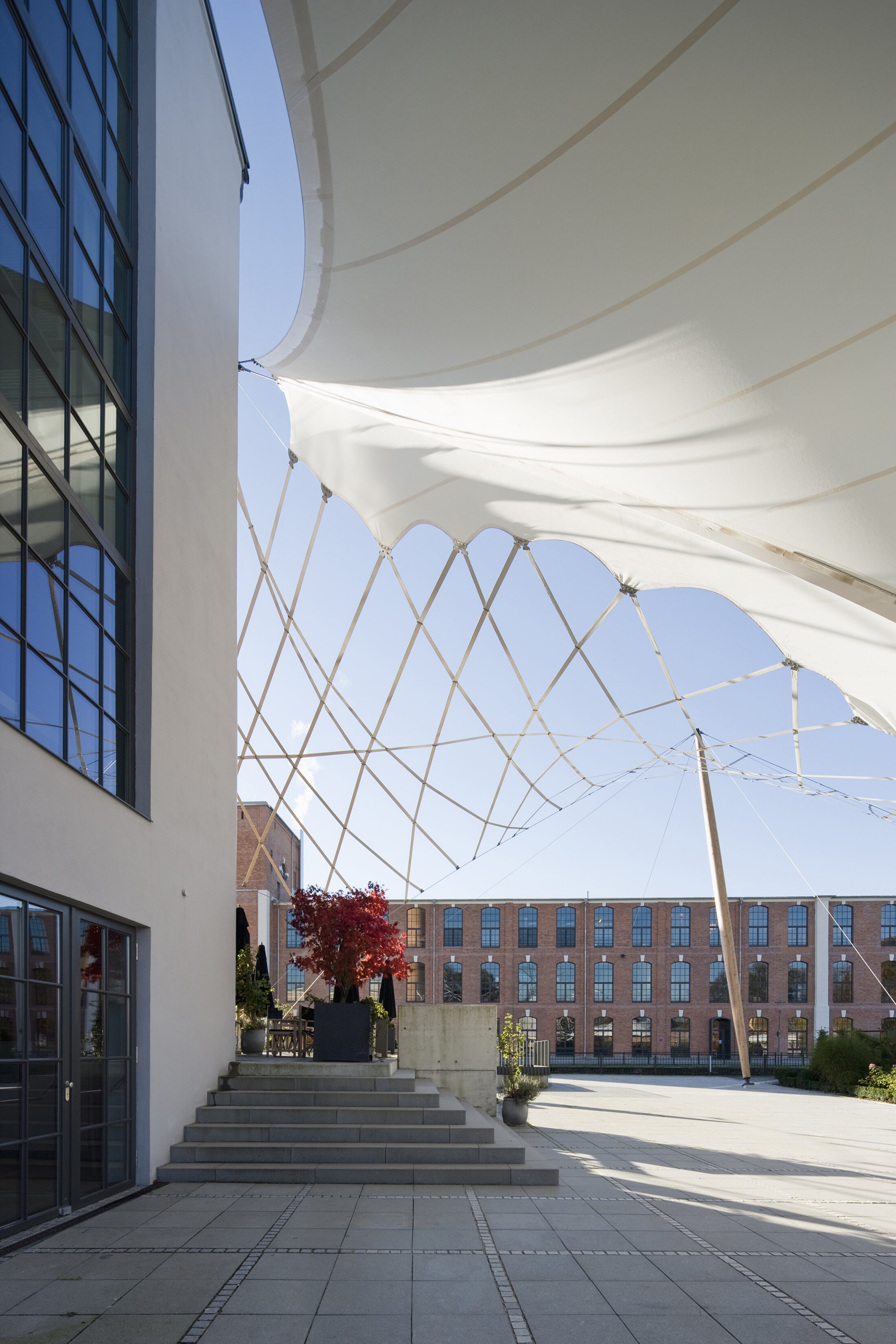 Project by Behnisch Architekturbuero, Boiler House. A white, rope-like net structure is located in the entrance area of ​​the boiler house. It is a modern building with a glass facade.