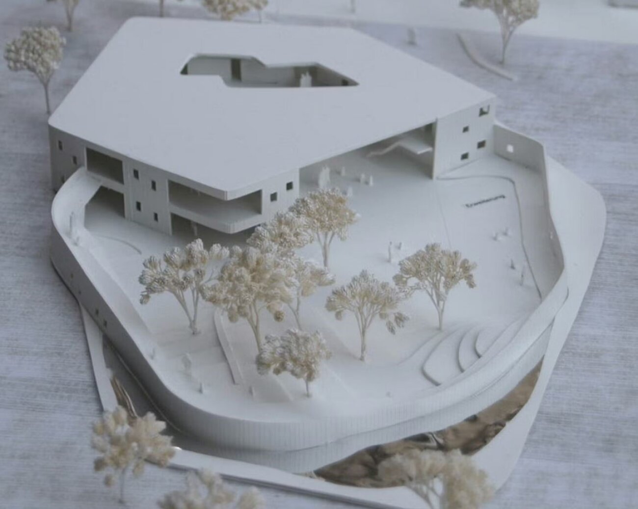 Project by Behnisch Architekturbuero, Townhall Heidelberg Schwetzinger Terasse. Scale model of a building with a central courtyard, surrounded by landscaped grounds with small trees and paths.